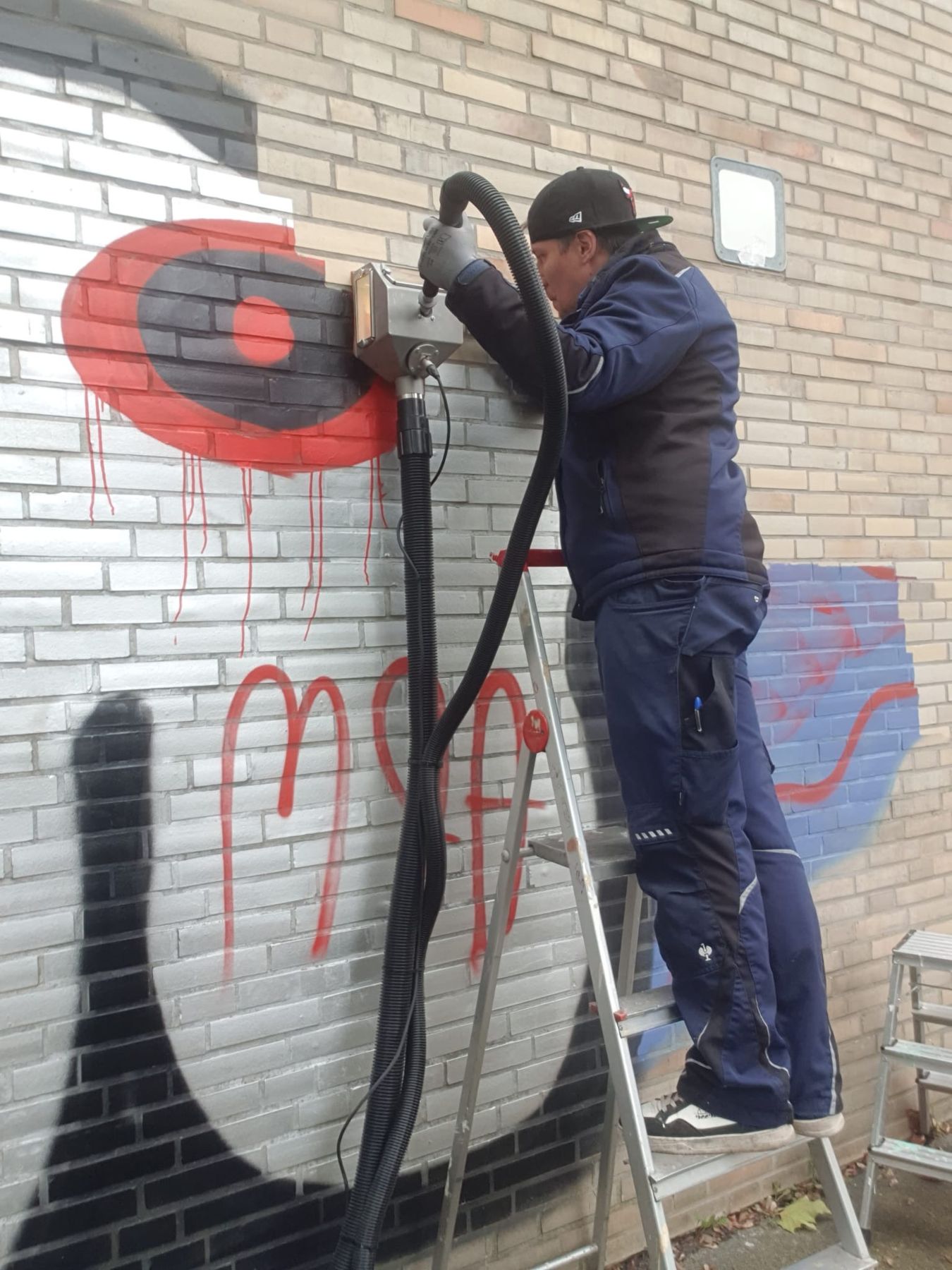 Mitarbeiter entfernt Graffiti mit Vakuumstrahltechnik