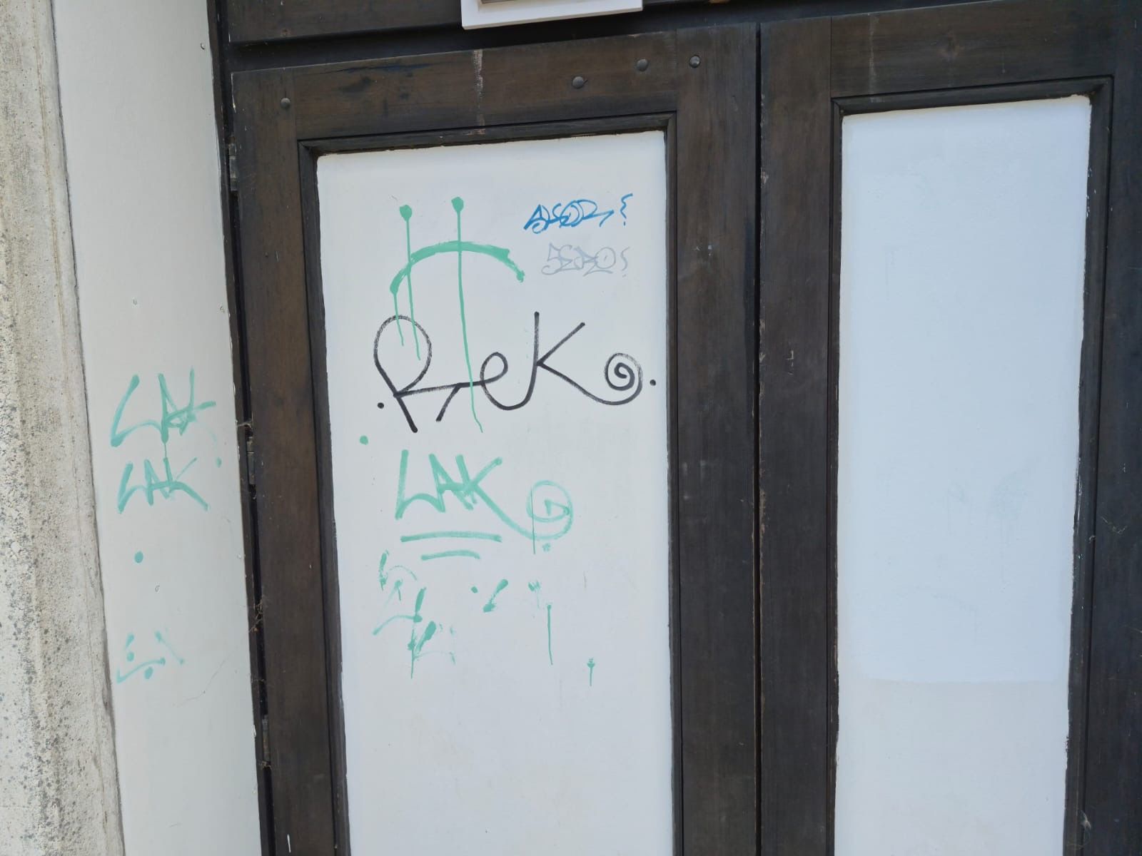 Tür mit Graffiti-Schmierereien vor der Reinigung