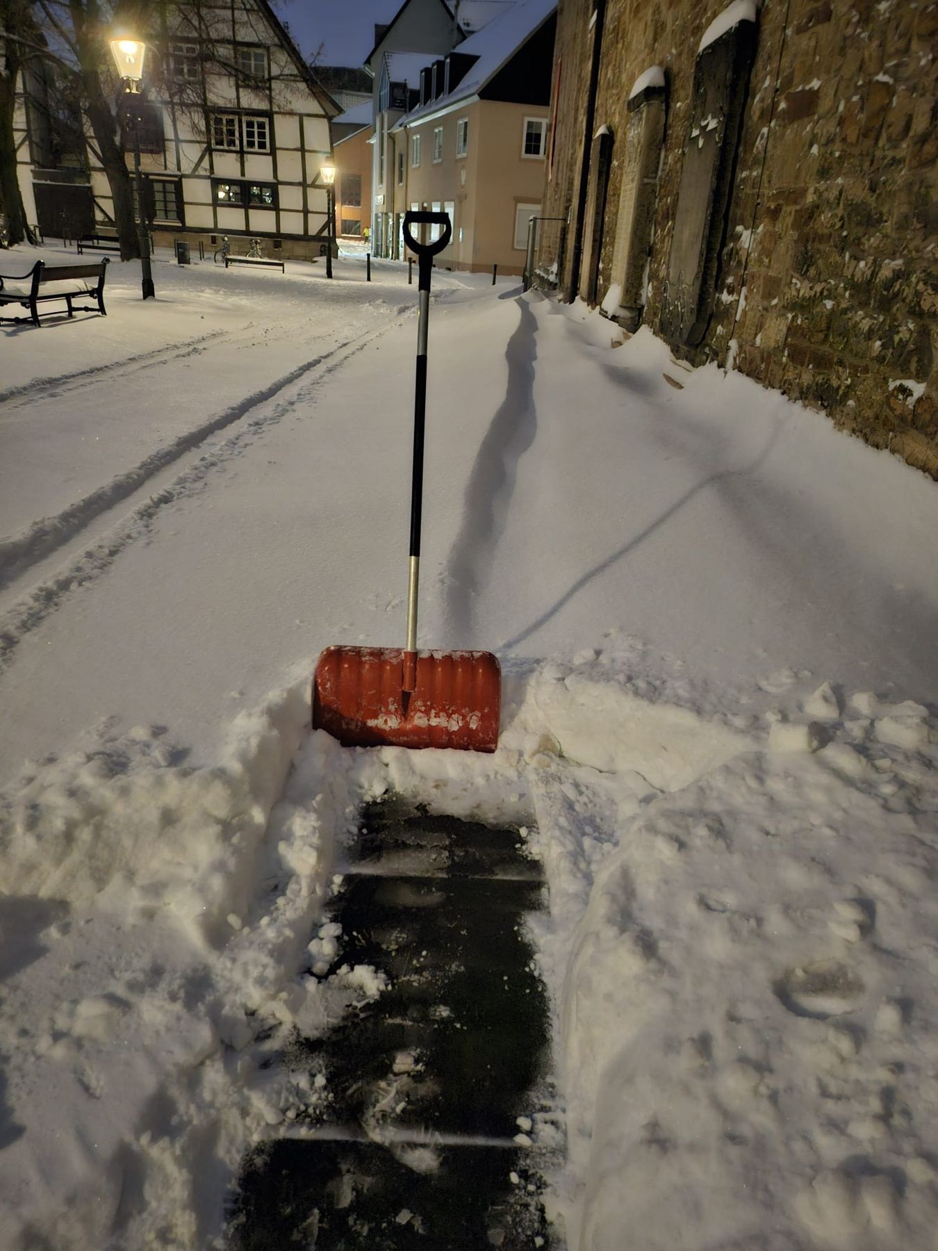 Schneeräumung mit Schneeschieber in der Altstadt am frühen Morgen